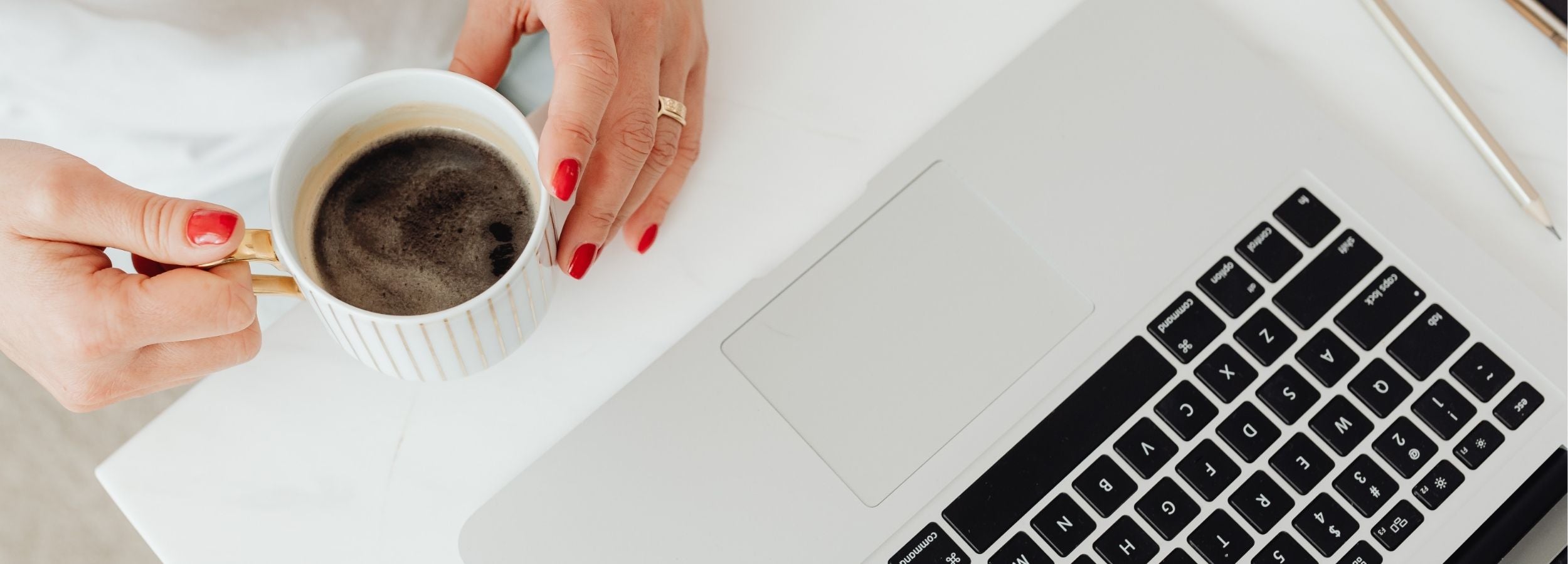 Minimal workspace scene with hands holding a coffee mug beside a laptop, representing thoughtful learning, personal growth, and intentional reflection through writing and education.